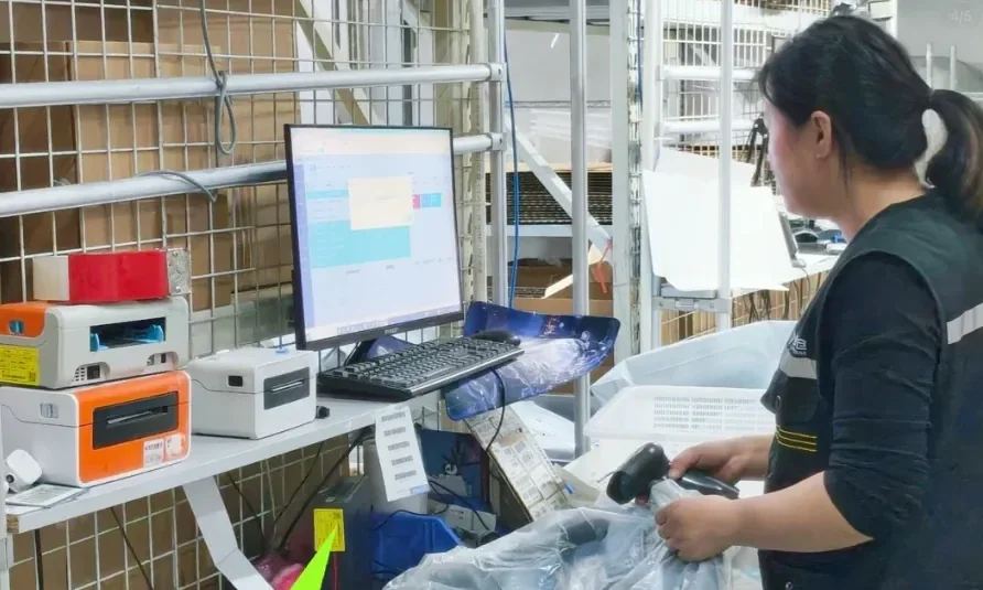Worker registering a parcel beside a warehouse computer