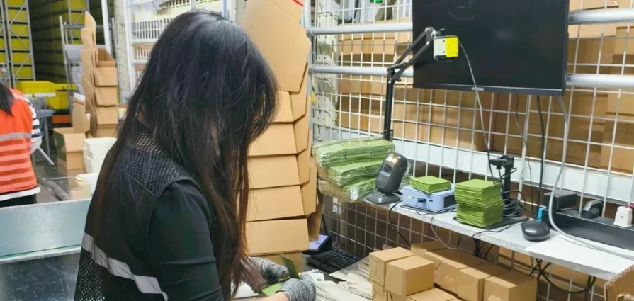 Worker recording a parcel at a warehouse workstation