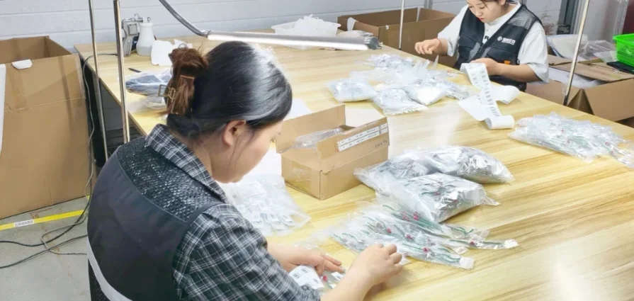 Operators checking and packing small products at a warehouse bench