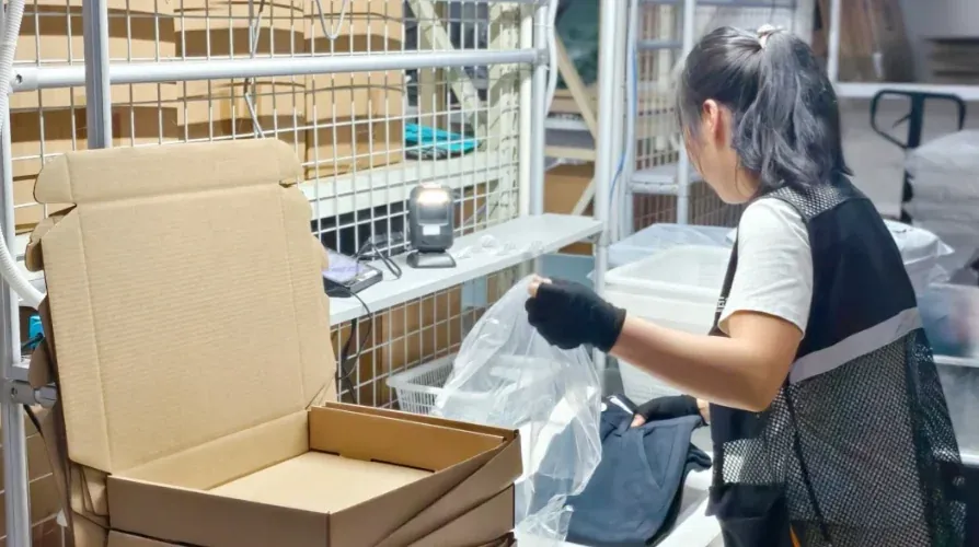 Warehouse worker preparing protective material beside an open carton